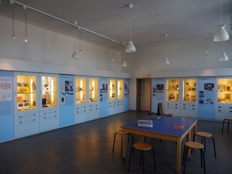 Ein Ausstellungsraum im Schulmuseum in Bremen. In der Mitte steht ein Tisch mit Büchern, an den Wänden sind Ausstellungsvitrinen und Plakate